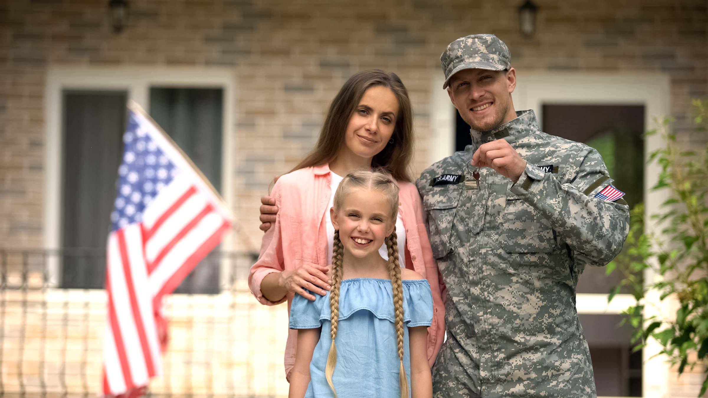 Veteran standing with his wife and daughter holding the key to their new home.