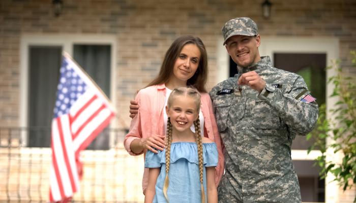Veteran standing with his wife and daughter holding the key to their new home.