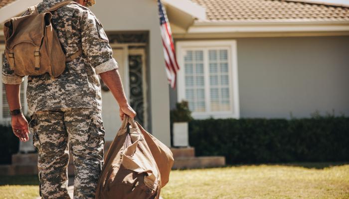 Soldier with PCS orders standing in front of his new home. 
