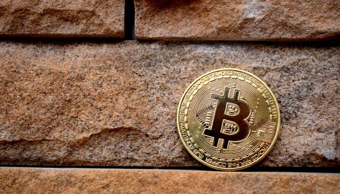Physical bitcoin leans on a brick wall.