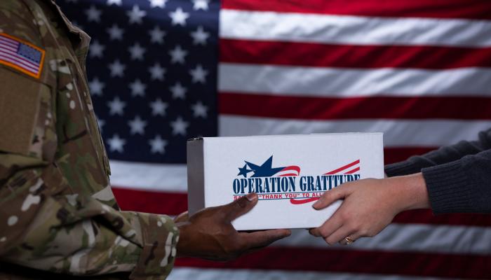 Woman hands soldier an Operation Gratitude package. 