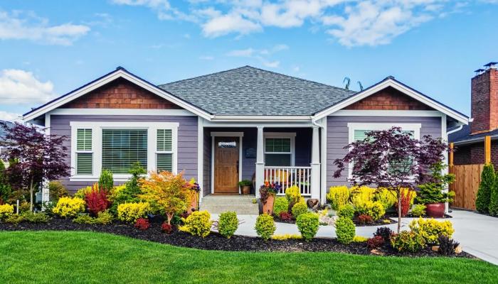 Front view of a purple house with a well groomed garden.