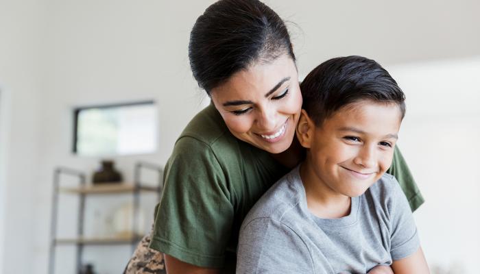 Latina mother smiling and holding her son. 