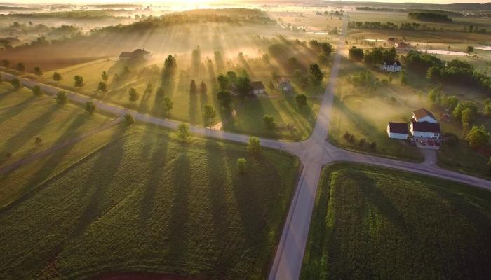 Aerial view of farm properties with a radiant sunrise.
