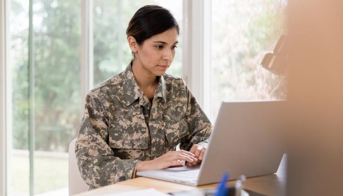 Soldier works on laptop in kitchen.