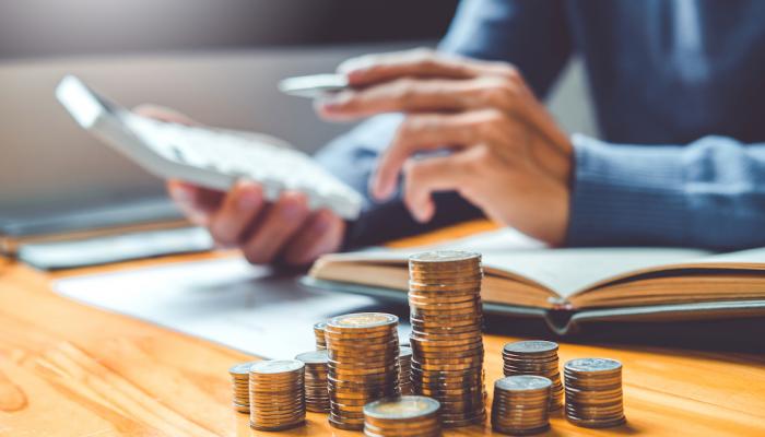 Man budgeting at a table with a stack of coins in front of him.