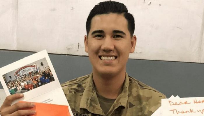 Soldier smiles while holding postcard that came with a care package.