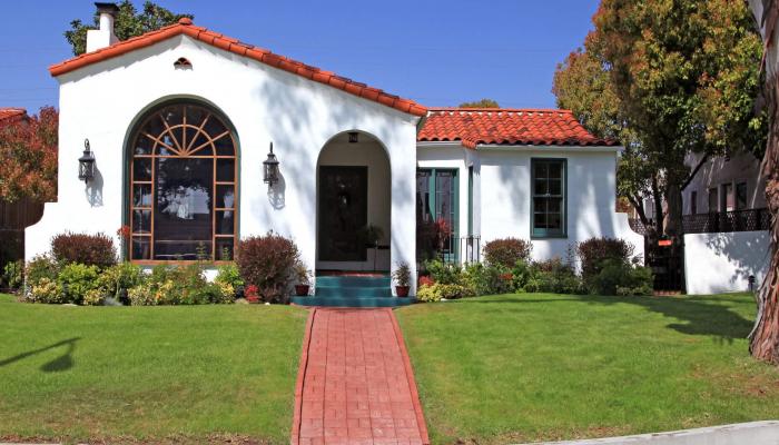 Front view of a Spanish style home with a clay tile roof and white walls.