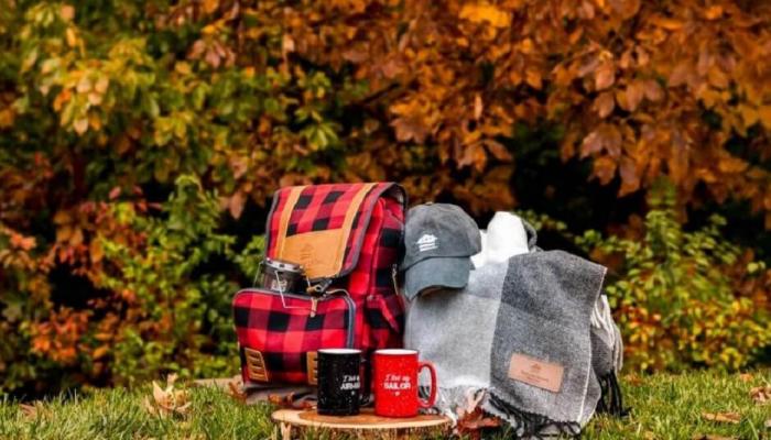 A collection of gifts including a backpack, hat, mugs and blanket.