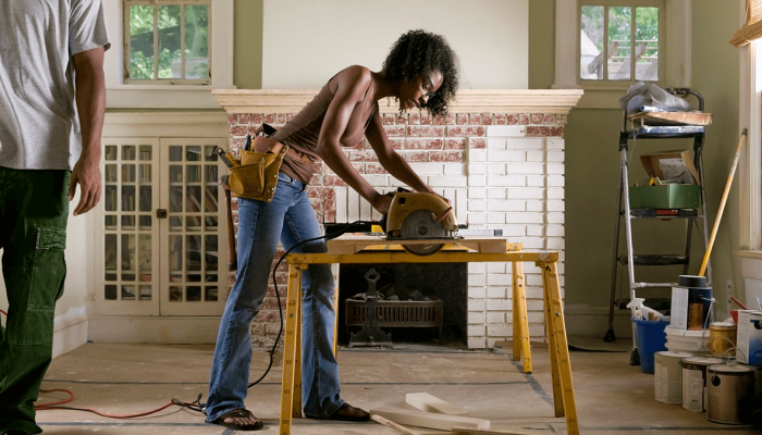 Woman using an electric saw while doing renovations in her home.