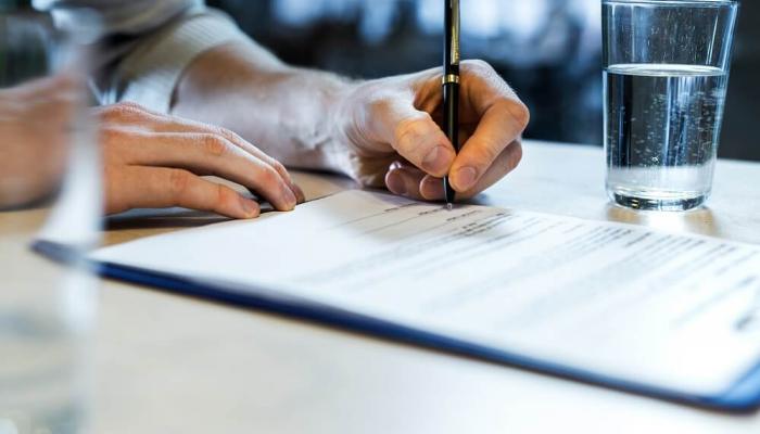 Close up of a man's hands signing a document.