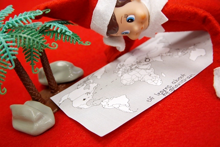 Elf on the Shelf looking at a map