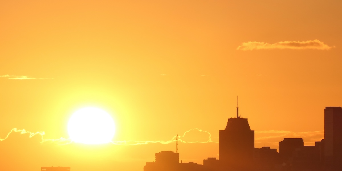 Sun shown over a city skyline on a hot day.