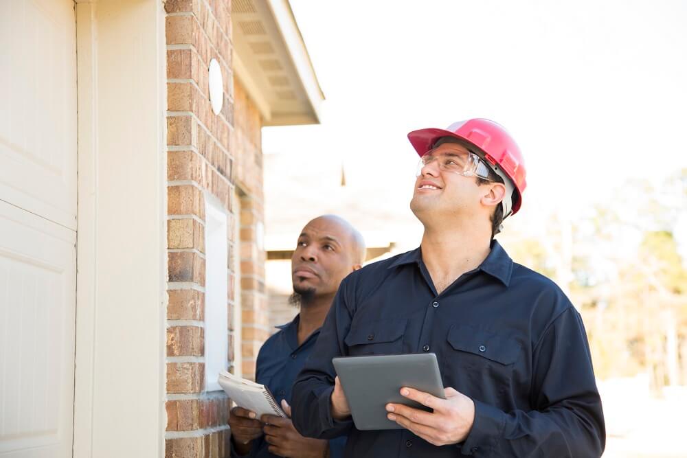 Two home inspectors evaluating the outside of a home.