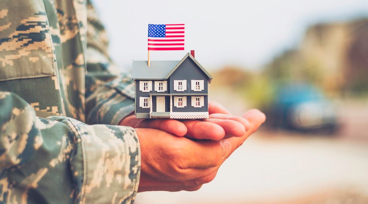 Veteran holding tiny house with American flag. 