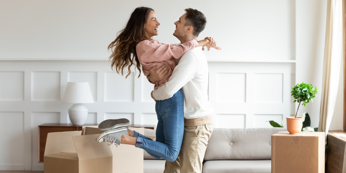 Overjoyed husband swings happy wife, excited to move in new home together.