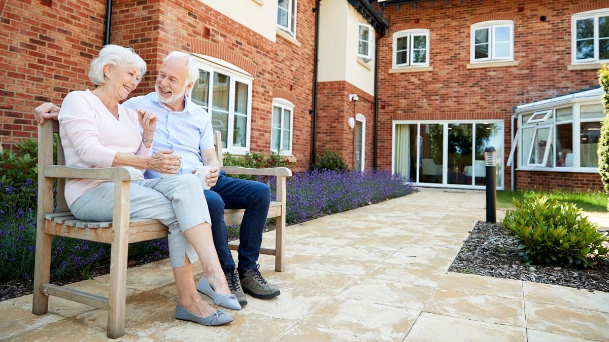 Older couple sit in garden at an age restricted community.
