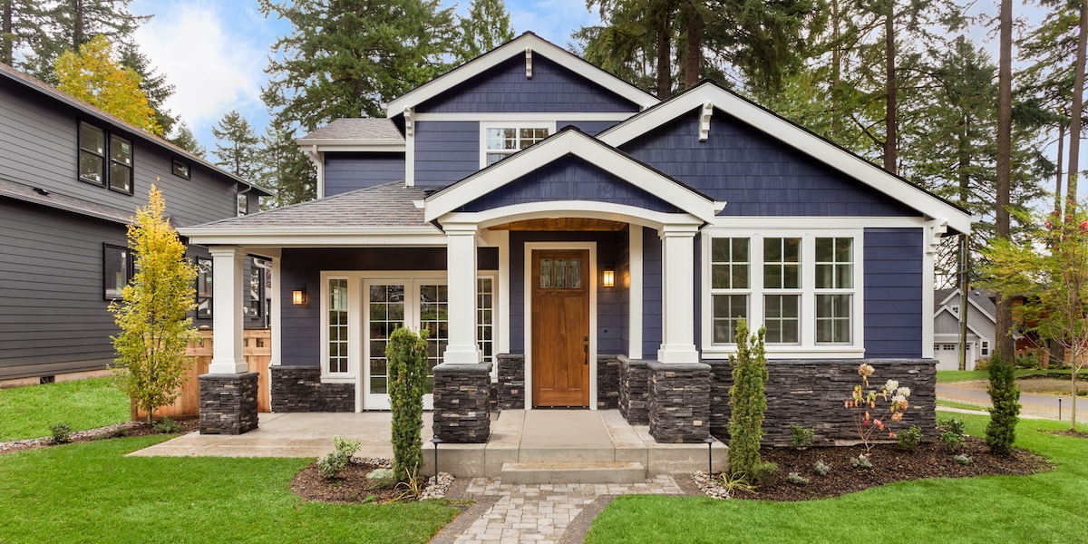 Exterior of a nice house with blue vinyl and a wood door.