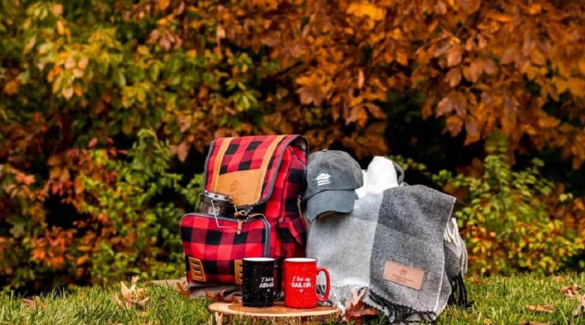 A collection of gifts including a backpack, hat, mugs and blanket.