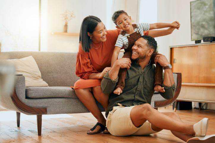 A happy family relaxing in their home and smiling at each other.