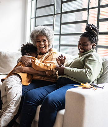 Two women and  a little boy sitting on a couch and lauging together