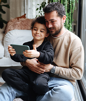 Father and son looking at something on iPhone.